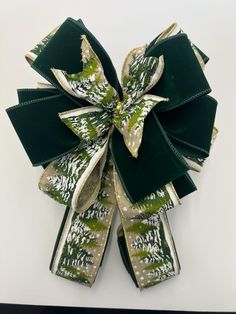 a green bow with white and gold designs on it's side, hanging from a wall