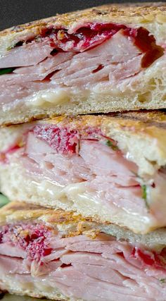 two ham sandwiches stacked on top of each other with cranberry sauce in the middle