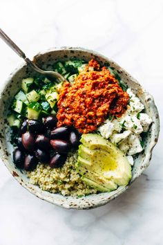 a bowl filled with different types of food on top of a white countertop next to a spoon