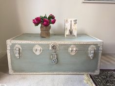 an old suitcase with flowers on top is sitting next to a photo frame and postcard