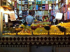 a man standing in front of a store filled with lots of fruits and veggies