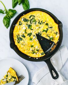 an omelet with spinach and cheese in a cast iron skillet on a white table