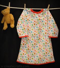 a teddy bear is hanging on a clothes line next to a baby's shirt