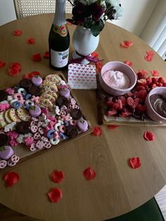 a table topped with lots of cookies and pastries next to a bottle of wine