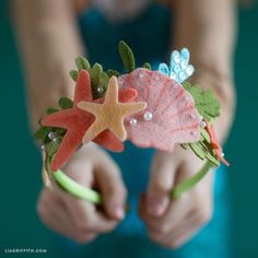 a close up of a child's hands holding a hair band with starfishs and seashells on it