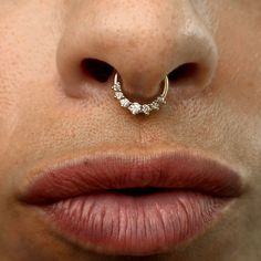 a woman's nose with a gold nose ring on top of her nose and two small diamonds in the middle