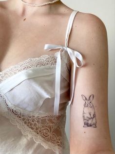 a woman with a rabbit tattoo on her left arm and right arm behind her shoulder