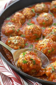 a pan filled with meatballs covered in sauce and garnished with parsley