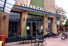 the outside of starbucks's coffee shop with tables and chairs