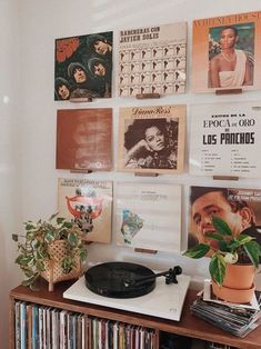 a record player sitting on top of a wooden table next to a wall filled with records