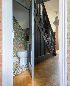 an open door leading to a bathroom with a toilet and staircase in the back ground