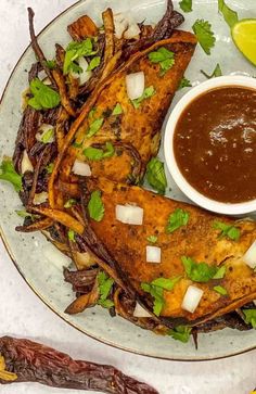 a white plate topped with fish and fries next to a bowl of dipping sauce on top of it