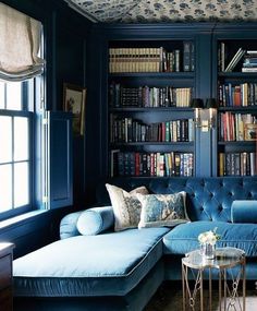 a blue couch sitting in front of a book shelf filled with books