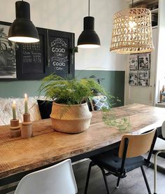 a dining room table with two hanging lights above it and a plant in the center