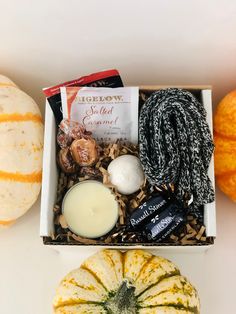 a box filled with candles, yarn and pumpkins on top of a white table