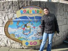 a woman standing in front of a sign with hello kitty on it's side