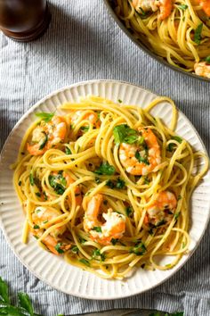 two plates of pasta with shrimp and parsley