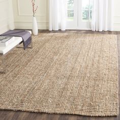 an area rug in the middle of a room with white curtains and wooden flooring