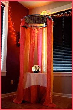 an orange and pink canopy bed in a room with lights on the wall behind it