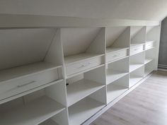 an empty room with white shelves and drawers