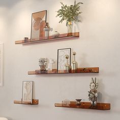 three wooden shelves on the wall with vases and other items sitting on top of them