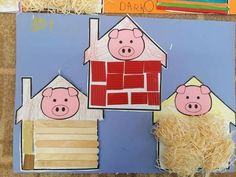 paper cut out of houses with pigs in the front and on the back, sitting next to shredded straw