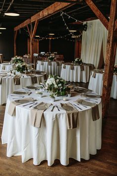 the tables are set up with white and brown linens for an elegant wedding reception