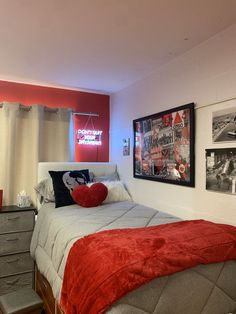 a bed room with a neatly made bed and pictures hanging on the wall above it