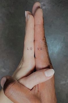 two hands holding each other with the word love written on them in cursive writing