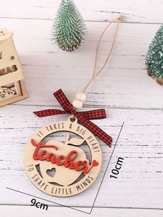 a wooden ornament with the words teacher hanging from it's side on a white table