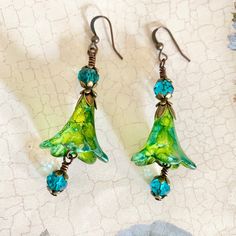 Adorable iridescent Green Flower Earrings, these colourful hand painted green flowers hang from filigree flute bead caps, they are finished with little crystals that are so eye catching and sparkly. These earrings are one of a kind and would make the most luxurious gift. Matching necklace available here: https://etsy.me/338DbVC ▪️ One of a kind, only one made. ▪️ lightweight and comfortable. ▪️ This item is ready for posting. ▪️ Lead and Nickel free components. ▪️SIZE: approximately 50mm. ▪️MATE Green Flower Earrings, Green Fairy, Hand Painted Earrings, Iridescent Green, Painted Earrings, Earrings Green, Boho Vintage, Elegant Necklaces, Earrings Boho