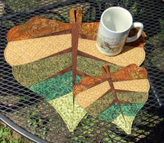 a coffee cup sits on top of a table next to a quilted placemat