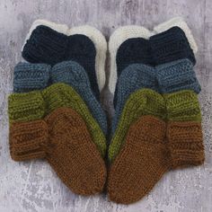 two pairs of knitted mittens sitting next to each other on a cement surface