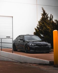 a black car parked in front of a garage door next to a parking meter and orange poles