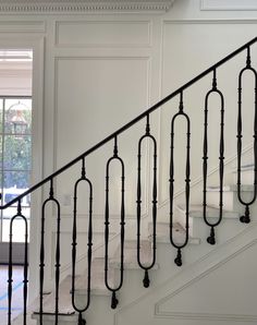 a staircase with wrought iron handrails in a white room next to a window