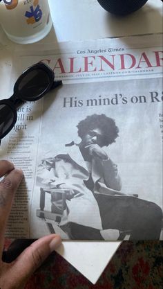 a person reading a newspaper with black glasses on top