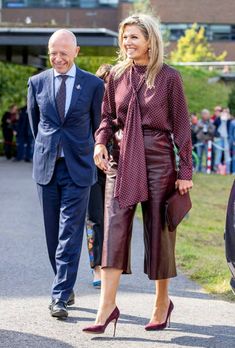 a man and woman walking down a street next to each other with people in the background