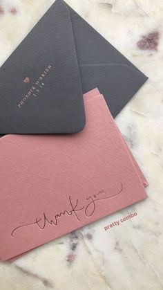 two envelopes with thank you written on the front and back, one in grey and pink