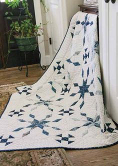 a blue and white quilt is on the floor next to a potted green plant