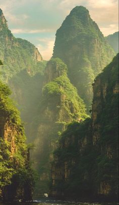 a river surrounded by mountains and greenery in the middle of the day with a boat on it