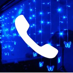 a phone is lit up in the dark with blue lights and butterflies hanging from it