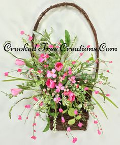 a basket filled with pink flowers on top of a white wall next to a plant