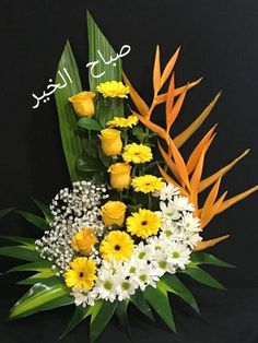 a bouquet of yellow and white flowers on a black background with green leaves in the center