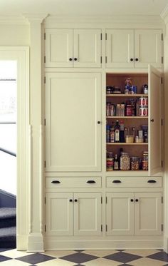 a kitchen with white cabinets and black and orange checkered flooring on the walls