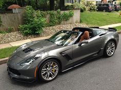 a gray sports car parked on the side of the road in front of a house