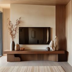 a living room with a large television on the wall and vases filled with flowers