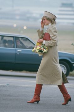 a woman is walking down the street talking on her cell phone while holding a bouquet of flowers