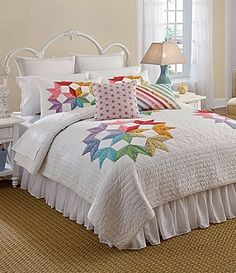 a bed with white sheets and colorful pillows