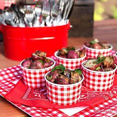 four red and white cups filled with food on top of a checkered table cloth