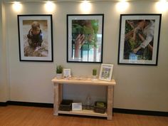 two framed pictures hang on the wall above a small table in a room with hard wood flooring